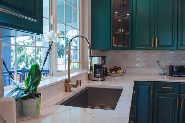 Well-equipped kitchen with green cabinets and coffee maker
