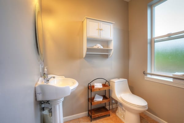 Modern bathroom with a sink, toilet, and storage shelf