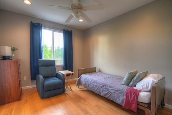 A well-lit bedroom with a blue chair, bed, and window