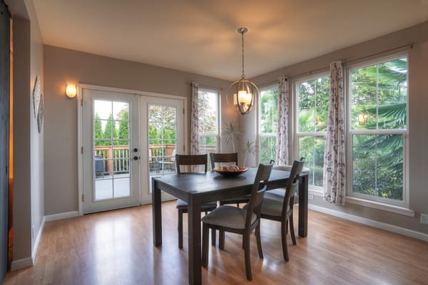 Bright dining room with a wooden table and chairs beside large windows