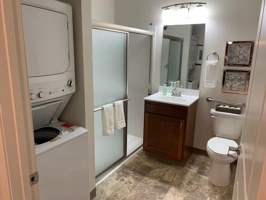 Compact bathroom featuring a washer and shower stall.