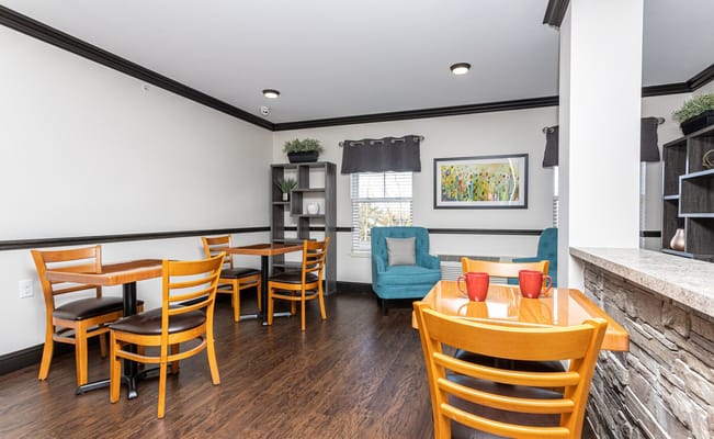 Bright common area with wooden tables and chairs at Lyndon Square Senior Apartments.