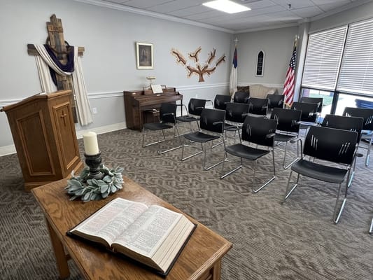 Interior view of a chapel setting with chairs and a Bible