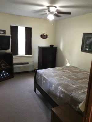 A cozy bedroom with a bed, dresser, and window