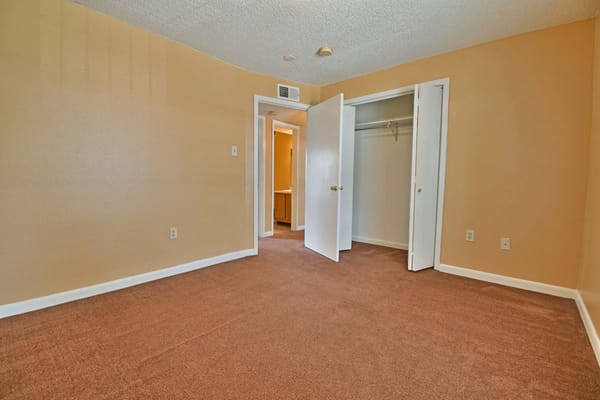 Empty bedroom with carpet and closet doors open