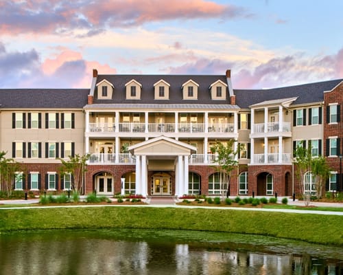 Exterior view of a senior living facility by a pond
