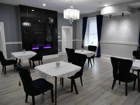 Dining area with tables and chairs, featuring a modern fireplace