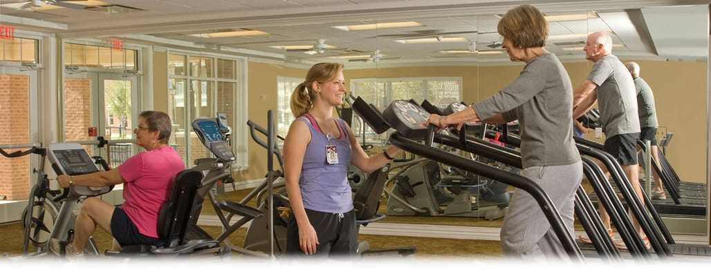 Residents using exercise equipment with staff assistance