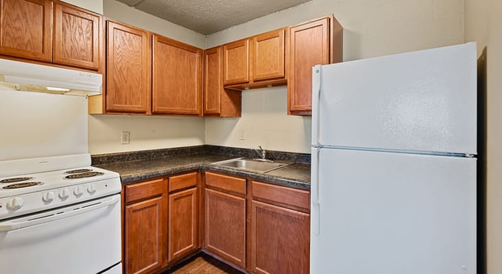 Kitchen area with wooden cabinets, stove, and refrigerator