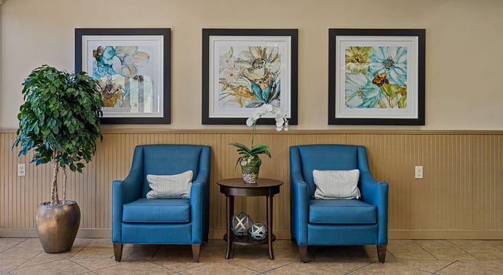 Two blue chairs and a small table with a plant in the lobby