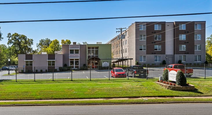 Exterior view of Jordan Square Senior Apartments with landscaped parking area.