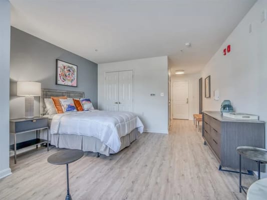 A spacious bedroom with a bed, nightstand, and dresser.