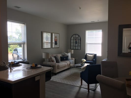 Spacious living room with a sofa, chairs, and natural light