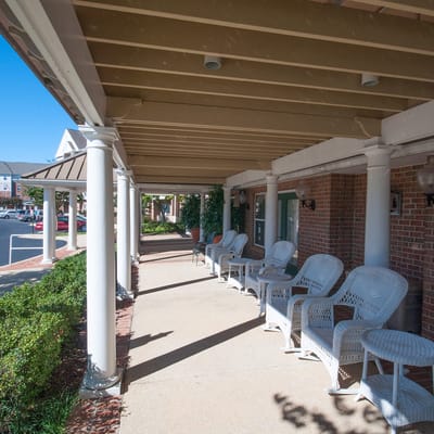 A shaded porch with white wicker chairs and a view of the garden