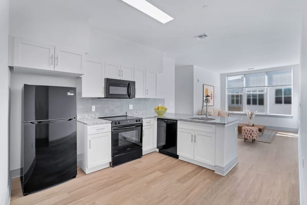 A modern kitchen featuring black appliances and white cabinetry.