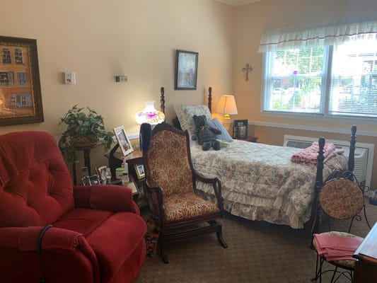 A cozy bedroom featuring a bed, red armchair, and decorative items.