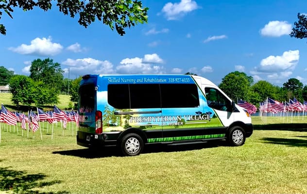 Facility transportation van parked in a field with flags