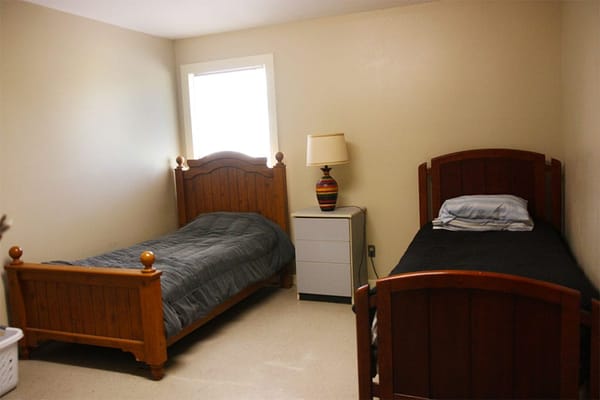 Shared bedroom with two wooden beds and a nightstand