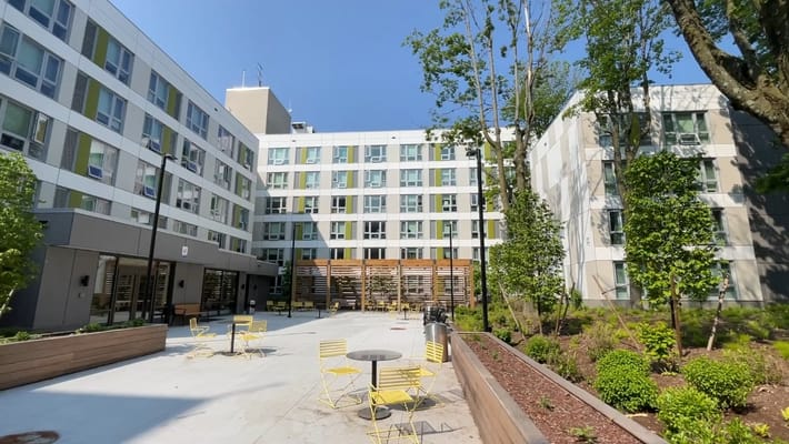 Outdoor courtyard with yellow chairs and greenery at Daniel F. Burns Apartments.