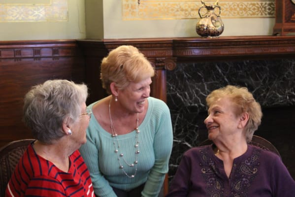 Caregivers conversing with two residents in a common area