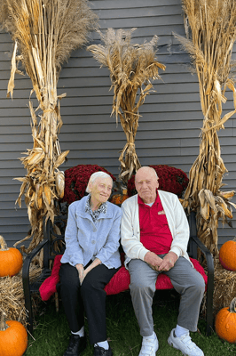 Two residents sitting together outdoors with autumn decorations