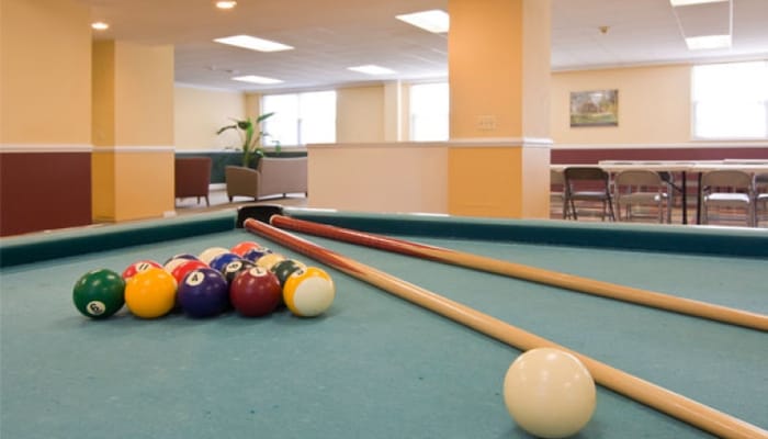 Billiard table with cue sticks in a common area