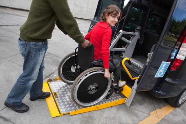 A caregiver assisting a woman in a wheelchair boarding a van