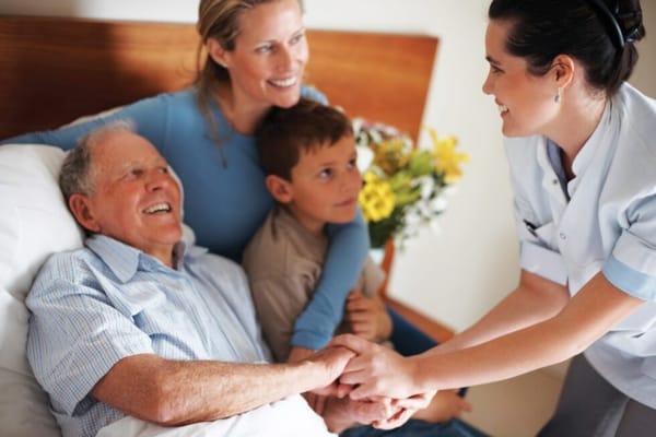 A caregiver assisting an elderly resident with family present