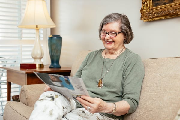 A smiling resident reading a magazine in a cozy living space
