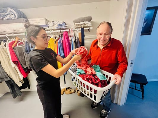 Staff assisting a resident with laundry in a facility