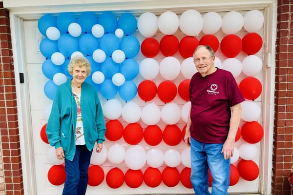 Residents posing in front of a festive balloon display