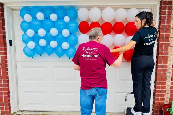Resident and staff decorating with patriotic balloons