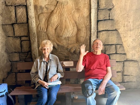 Two residents seated on a bench in a common area
