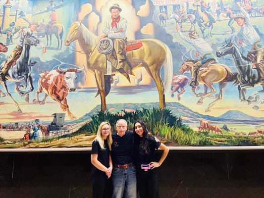 Residents and staff smiling in front of a mural