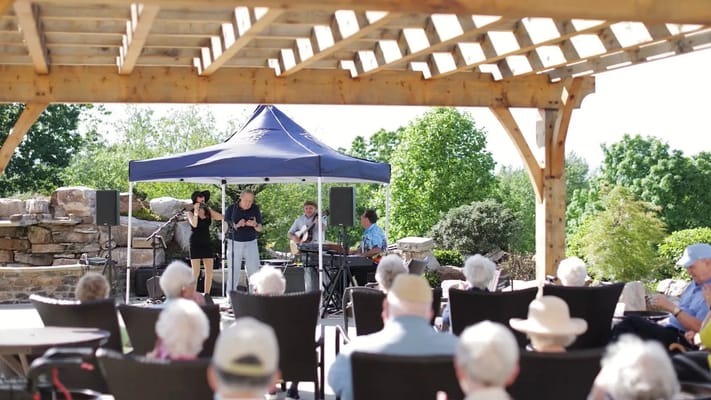 Residents enjoying live music outdoors at a senior living facility