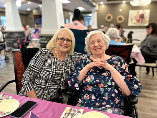 Two women smiling at a table in a common area