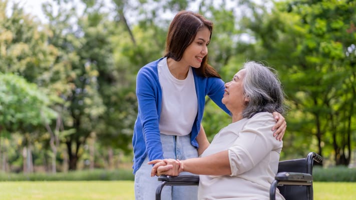 A caregiver interacting with a senior woman outdoors