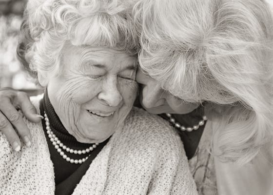 A smiling elderly woman and caregiver sharing a moment