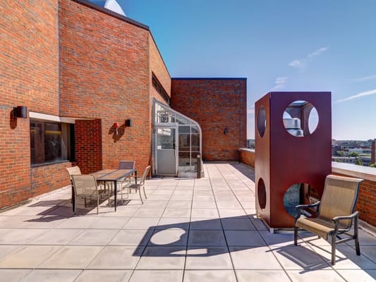 Outdoor rooftop terrace featuring seating and a decorative structure.