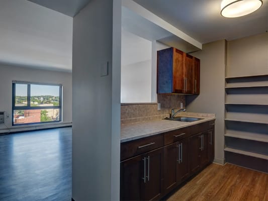 A modern kitchen with wooden cabinets and a window view.