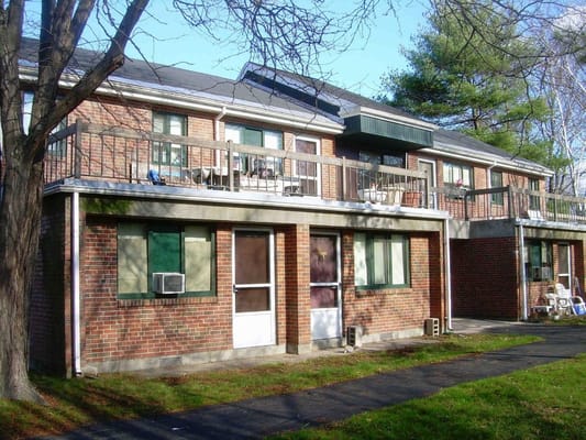 View of the exterior of Norumbega Gardens featuring brick buildings and balconies.