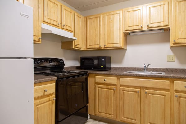 Bright kitchen area with wooden cabinets and appliances