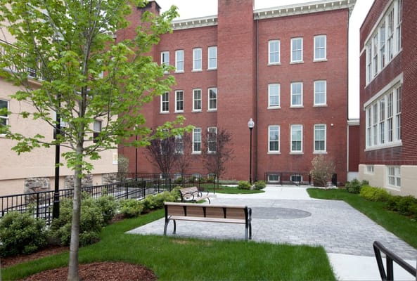 Courtyard with benches and trees at Sacred Heart Apartments