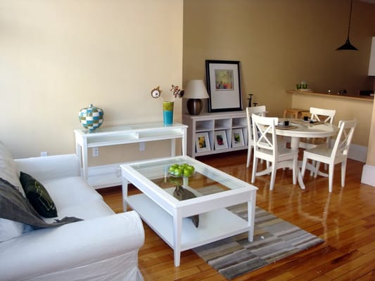 Bright living room featuring a white sofa, coffee table, and dining area.