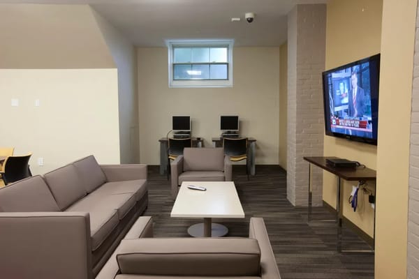 Seating area with a television and computers in the background