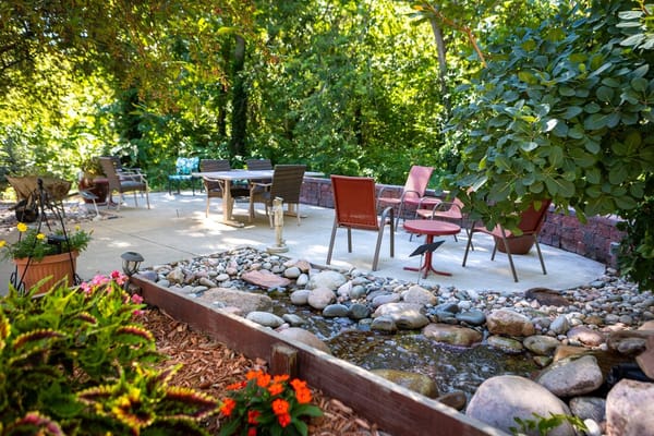 Outdoor seating area surrounded by greenery and flowers
