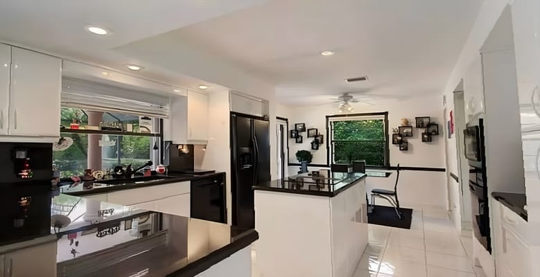 Modern kitchen area with white cabinets and dark countertops