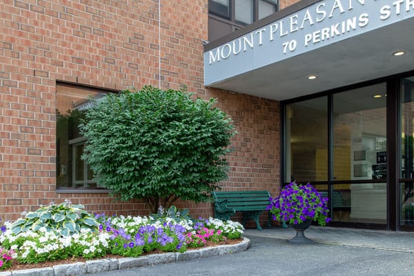 Exterior view of Mt. Pleasant Apartments with flowers and bench