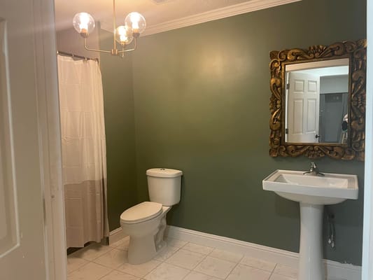 Modern bathroom with green walls and elegant fixtures.