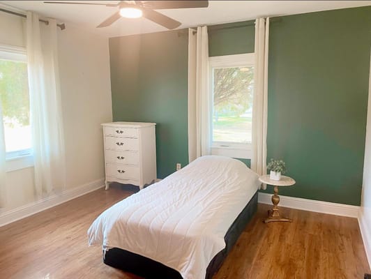A cozy, well-lit bedroom with a bed, dresser, and window view.